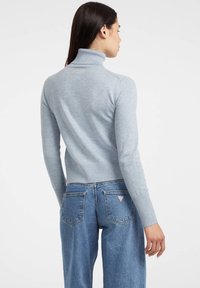Maglione a collo alto blu chiaro con dettagli a costine, maniche aderenti e vita attillata, abbinato a jeans dritti di lavaggio medio.