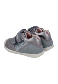 Zapatos infantiles grises con una combinación de cuero liso y tejido texturizado, que cuentan con una correa de velcro, puntera redondeada y una suela flexible.