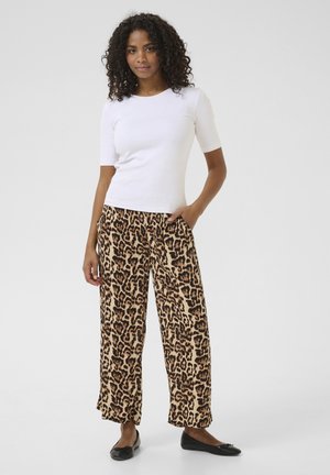Haut ajusté à manches courtes, blanc, associé à un pantalon large à imprimé léopard, ample. Le tissu est doux ; les pantalons ont des poches latérales et une taille élastique.