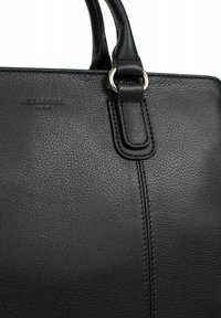 Borsa a mano in pelle nera con finitura testurizzata, caratterizzata da un'accento in metallo a forma di anello e cuciture in contrasto lungo la cucitura. Logo del brand impresso.
