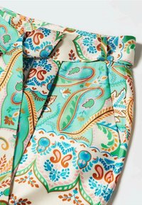 Tissu à motifs multicolores présentant des dessins cachemire en tons turquoise, pêche et marron avec des accents plissés à la taille.