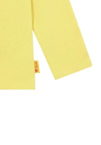 Camisa de manga larga amarilla, hecha de algodón suave, con una etiqueta que presenta una cara de dibujos animados y costuras bien hechas.