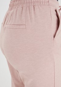 Roze joggers van zacht, textuurstof. Voorzien van een elastische tailleband en zijzakken. Eenvoudig, gestroomlijnd ontwerp zonder zichtbare patronen.