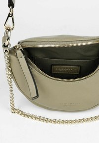 Borsa rotonda di colore verde oliva con una finitura liscia, apertura con zip e tracolla in catena argentata. L'interno presenta una fodera in tessuto e un logo.