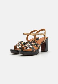 Sandalias de tacón trenzadas con un empeine multicolor trenzado, plataforma negra y tirante dorado en el tobillo con detalle de hebilla.