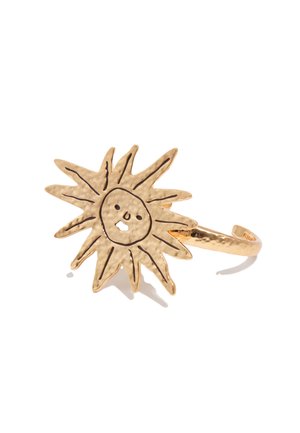 Anillo de tono dorado con un diseño de sol martillado que presenta un rostro simple y rayos grabados en negro sobre un fondo blanco.