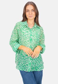 Green sheer blouse with a leopard print design, featuring a button-down front, collar, and long sleeves. Made from lightweight fabric.