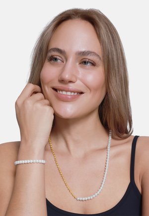 Perlenarmband und -kette mit weißen Perlen und goldenen Akzenten. Die Kette ist gestapelt, hat eine glatte Textur und eine kreisförmige Form.