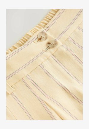 Light yellow fabric with vertical pink and blue stripes. Features a frilled waistband and two transparent buttons near the top.