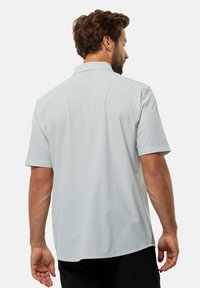 Korte mouwen, lichtblauw shirt met een textuurmotief, met knoopsluiting op de kraag en een rechte zoom, gezien vanuit de achterkant.
