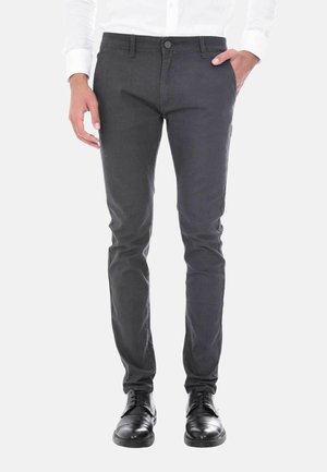Pantaloni grigi slim-fit con un delicato motivo testurizzato, dotati di chiusura con bottone e zip, tasche frontali e indossati con scarpe eleganti nere.