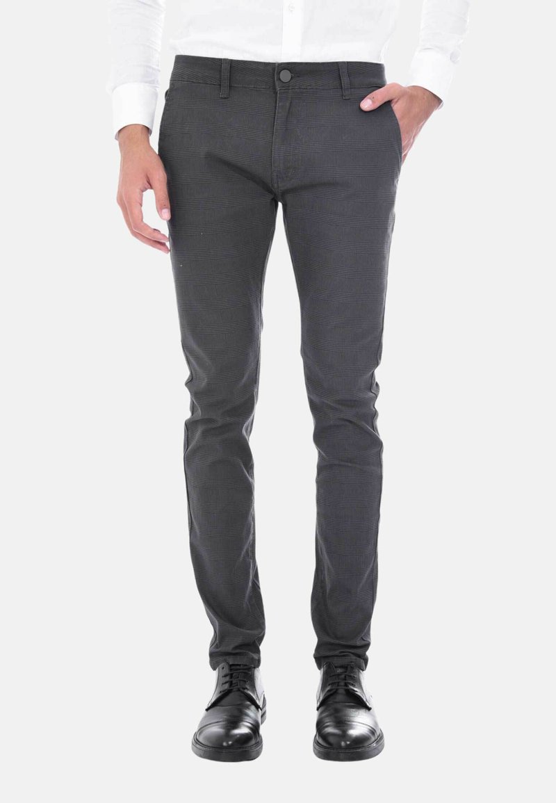 Pantaloni grigi slim-fit con un delicato motivo testurizzato, dotati di chiusura con bottone e zip, tasche frontali e indossati con scarpe eleganti nere.