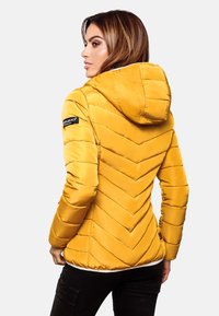 Yellow puffer jacket with a hood, featuring chevron quilted pattern and black logo accents. Smooth satin finish and fitted design.