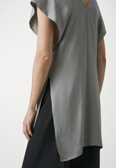 Gray, silk-blend top with a V-neck, cap sleeves, side slits, and a soft texture; paired with black fabric bottoms.
