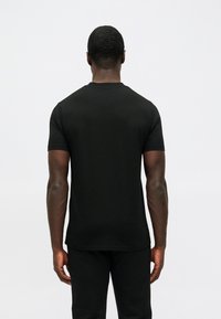 Μαύρο κοντομάνικο μπλουζάκι, casual εφαρμογή, φτιαγμένο από μείγμα βαμβακιού, με απλή υφή, απλός σχεδιασμός με λαιμόκοψη τύπου crew, χωρίς εμφανή σχέδια ή διακοσμητικά στοιχεία.