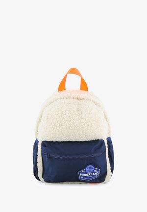 Petit sac à dos avec tissu blanc duveteux, poche avant zippée bleu marine, poignée orange et écusson logo Timberland.