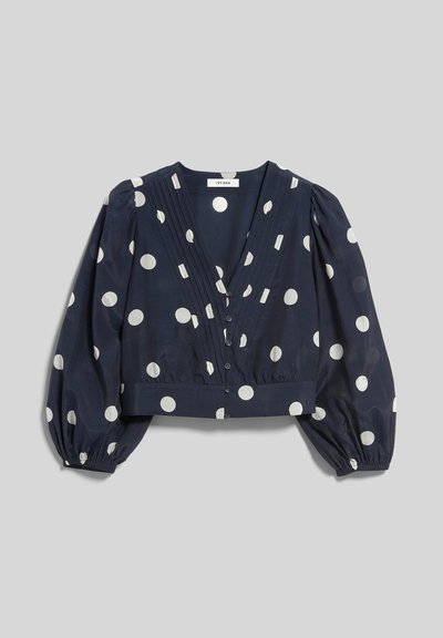 Tengerészkék rövidített blúz fehér pöttyökkel, mély V-nyakkivágással, gombos elejjel és hosszú, felpuffasztott ujjak rugalmas mandzsettákkal.