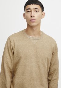 Beige sweatshirt met een klassieke ronde hals, textuurstof en subtiele verticale stikseldetails op de hals. Regular fit.