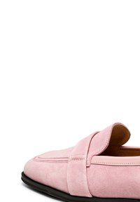 Mocassino in suede rosa con punta arrotondata, caratterizzato da una texture morbida, dettagli cuciti e una suola nera a contrasto. Design con retro aperto.