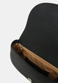 Borsa nera testurizzata con patta curvata, interno dorato e tasca con zip. Presenta una chiusura a bottone dorata e bordi lisci.