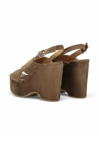 Bruine suede platform sandalen hebben een uitsnijdingen ontwerp en een verstelbare enkelband. De wiggenhak heeft een gebogen silhouet en een gladde afwerking.