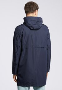 Granatowa wodoodporna parka z kapturem, długimi rękawami i wentylacją z tyłu. Posiada gładką fakturę i luźny krój, zaprojektowana z myślą o komforcie i ochronie.