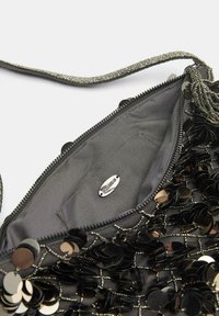 Sort taske med palietter, lynlås og en tekstureret inderside. Har et sølvfarvet mærke med mærkenavn og en dekorativ rem.