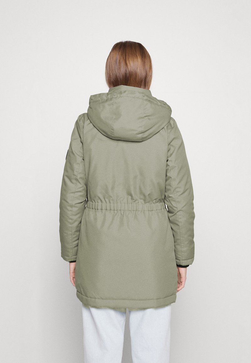 Veste rembourrée vert kaki avec capuche, taille cintrée, manches longues et texture lisse et mate. Pas de logos ni de motifs visibles.