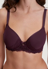 Paarse bh met gladde cups en een kant onderband, versierd met een strikje en logo detail in het midden, verstelbare bandjes.