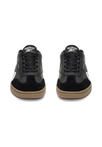 Zapatillas negras Reebok con materiales de ante y cuero, puntera redonda, cordones negros y suelas de goma color canela; con detalles blancos en los costados.