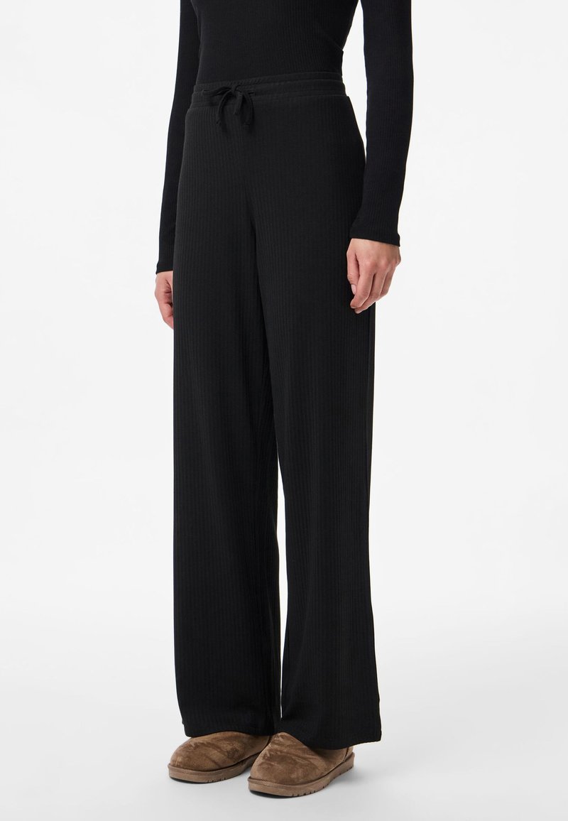Czarne, prążkowane spodnie o szerokich nogawkach, z elastycznym paskiem i sznurkiem, cechujące się miękką fakturą i luźnym krojem.