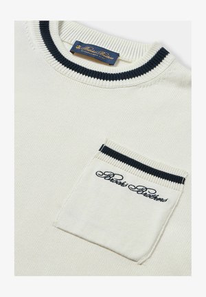 White knit sweater with a navy trimmed crew neck and pocket. Features embroidered logo on the pocket. Smooth texture, casual design.