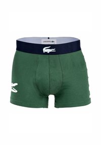 Boxers de algodón verdes con una cinturilla elástica azul marino que presenta el logotipo de Lacoste en blanco. Acento lateral con el icónico cocodrilo de la marca.