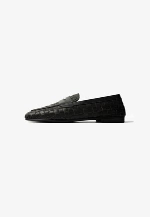 Black woven leather loafer with a low heel and a strap detail across the upper, shown in a side profile on a white background.