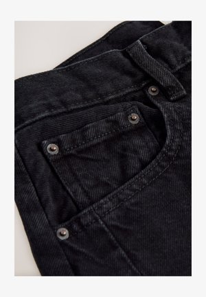 Čierne džínsy z denimu s vysokým pásom, s malým predným vreckom, kovovými ozdobami a textúrovaným povrchom látky.