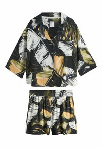 Conjunto de camisa de manga corta y pantalones cortos en blanco y negro, con un gran estampado de hojas en tonos amarillos y verdes, con cintura elástica.