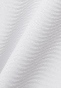Primer plano de tela blanca con textura acanalada vertical fina y pliegues suaves que crean sombras y reflejos sutiles.