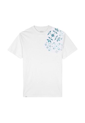T-shirt en coton blanc avec un design floral bleu sur le coin supérieur gauche, comportant des fleurs et des feuilles variées dans différentes nuances de bleu.