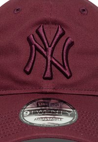 Sarkans beisbola cepure ar izšūtu NY logo. Aprīkota ar regulējamu siksnu, noapaļotu malu un teksturētu audumu. Uz birkas rakstīts "9TWENTY ADJUSTABLE".