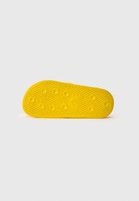 Yellow rubber shoe sole featuring a textured, diamond pattern and circular raised accents. Smooth edges with a rounded toe.