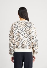 Leopardmönstrad sweatshirt i beige och svart, mjukt tyg, lös passform, ribbade ärmslut och nederkant, med rund hals.