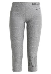 Szare legginsy wykonane z teksturowanej tkaniny, z logo na pasku w talii i napisem "NIKE" drukowanym pionowo na dolnej części nogawki. Krótki krój.
