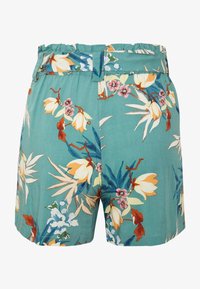 Teal shorts med ett volangmidja och bälteshällor som har ett färgglatt blommönster i gula, rosa, vita och blå toner.