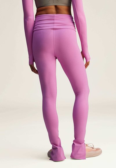 Rosa leggings gjorda av elastiskt material med hög midja och åtsittande design. Har utsvängda nederkanter och en mjuk textur.