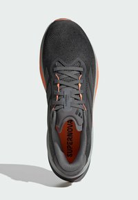 Scarpa da corsa da uomo con tomaia in maglia nera, dettagli arancioni, lacci grigi e colletto imbottito. Presenta una suola ammortizzata per il massimo comfort.