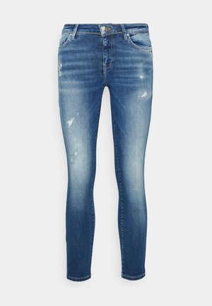 Jean skinny bleu délavé avec détails usés, design à cinq poches, fermeture avant par bouton et fermeture éclair.