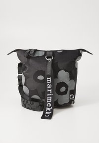 Black floral backpack made of durable fabric, featuring a zip closure, adjustable strap, and a logo detail in white.