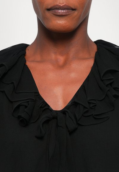 Zwarte blouse met een V-hals, gestructureerde ruffles rond de kraag en een strikdetail aan de voorkant. Gemaakt van lichtgewicht stof.