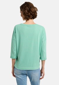 Hellgrünes gestreiftes Oberteil mit lockerer Passform, drei Viertelärmeln und weitem Halsausschnitt, aus weichem Stoff; minimalistisches Design.