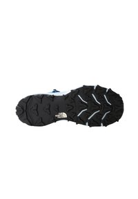 Semelle de chaussure en caoutchouc noir avec des motifs de semelle profonds et agressifs, et un logo blanc. Conçue pour offrir une traction sur des surfaces variées.